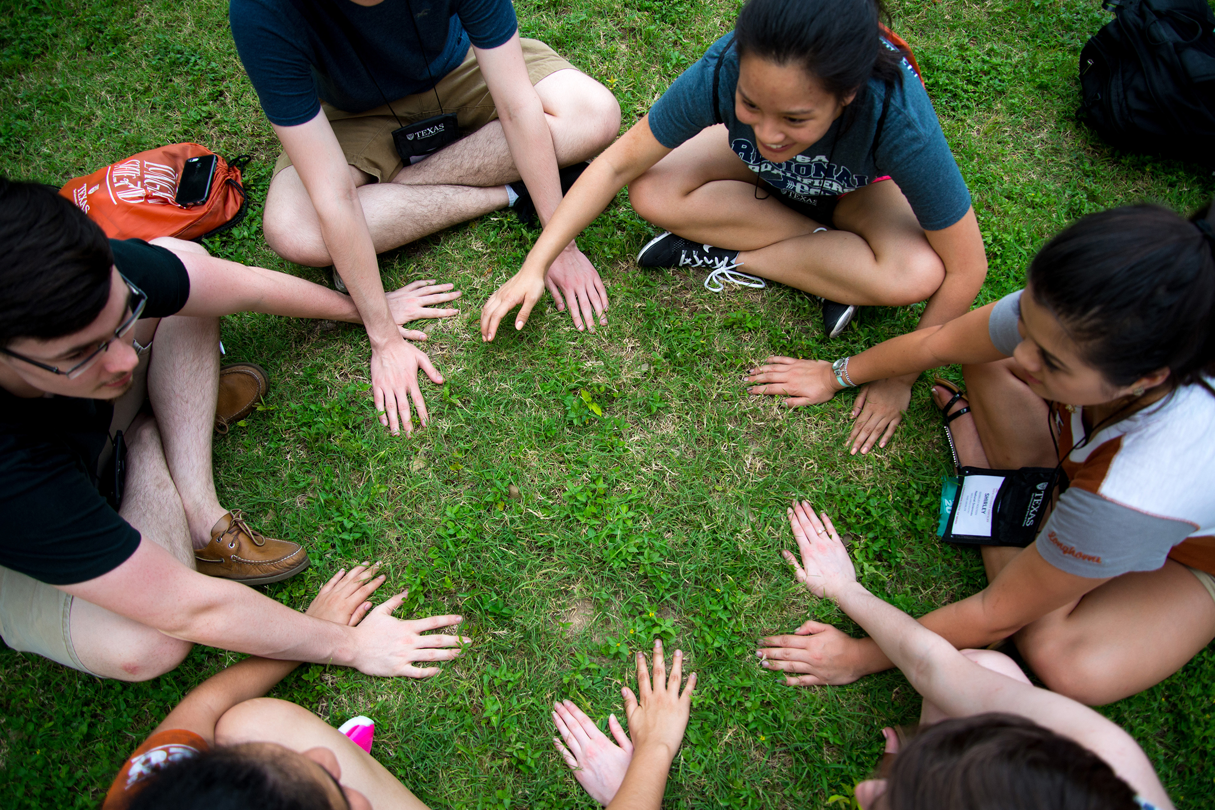 Freshman students sit in a circle on the grass near the UT turtle pond at a 2016 orientation.