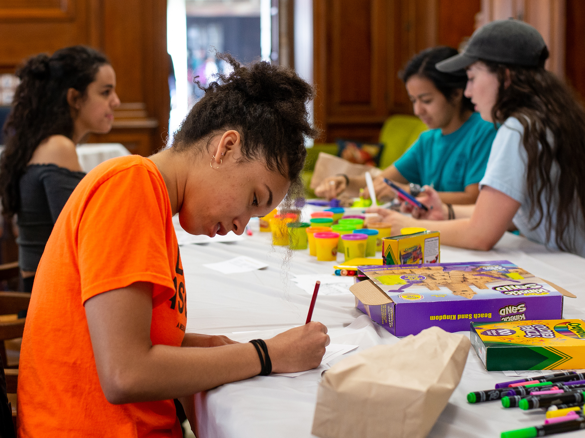 Students at a table socializing and engaging in arts and crafts activites as part of a "destress" space offered by the college.