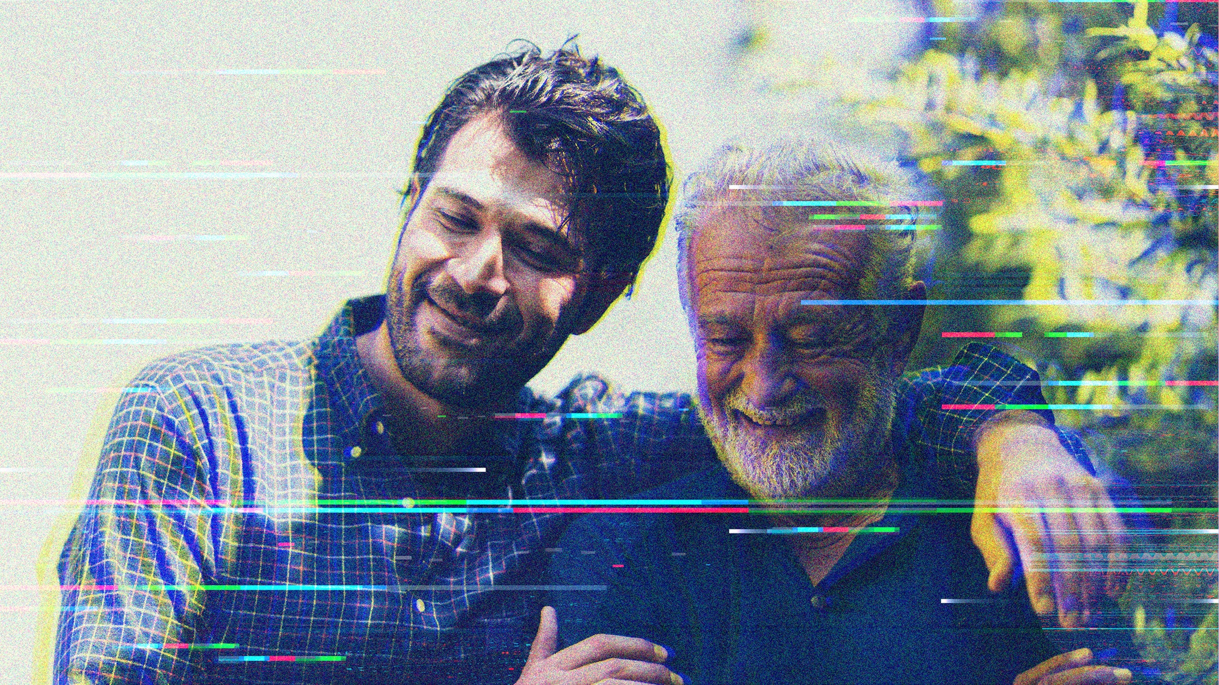 A younger man with dark hair and a beard, left, sits beside an older man with white hair. The younger man has his arm around the shoulders of the older man. Overlaid on the image are digital distortion lines.