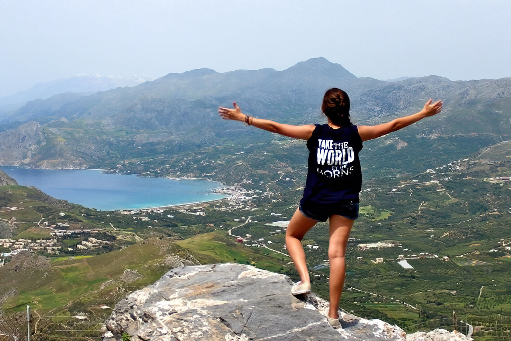 A student stands with arms stretched on a mountain