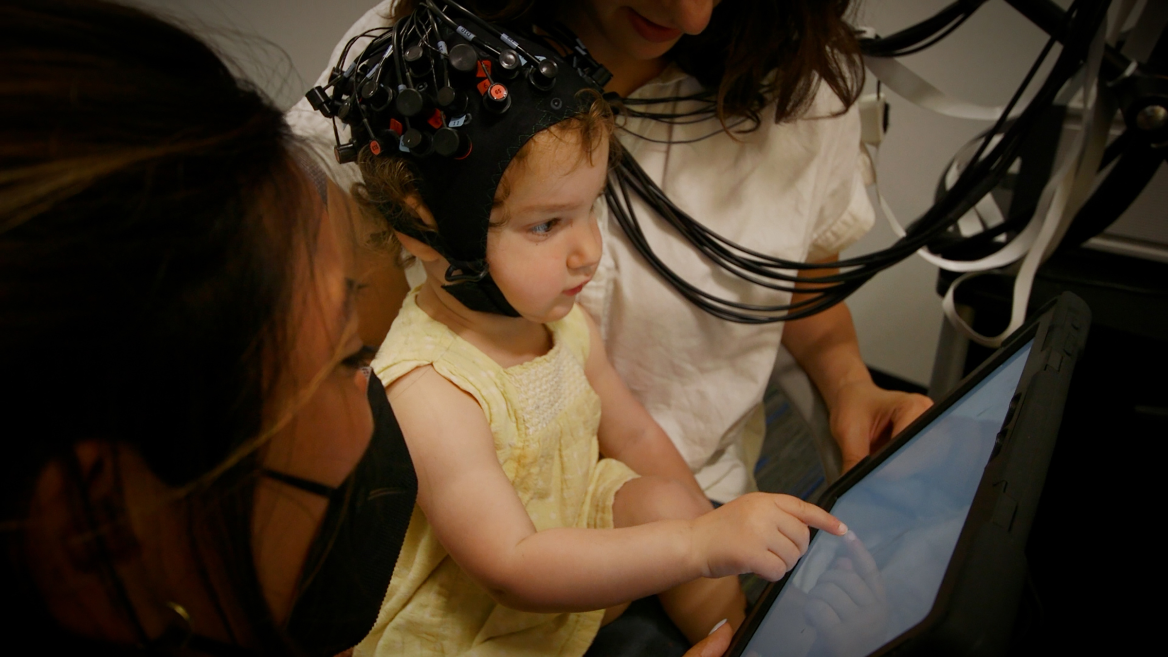 A child wearing a black cap touches a touchscreen computer