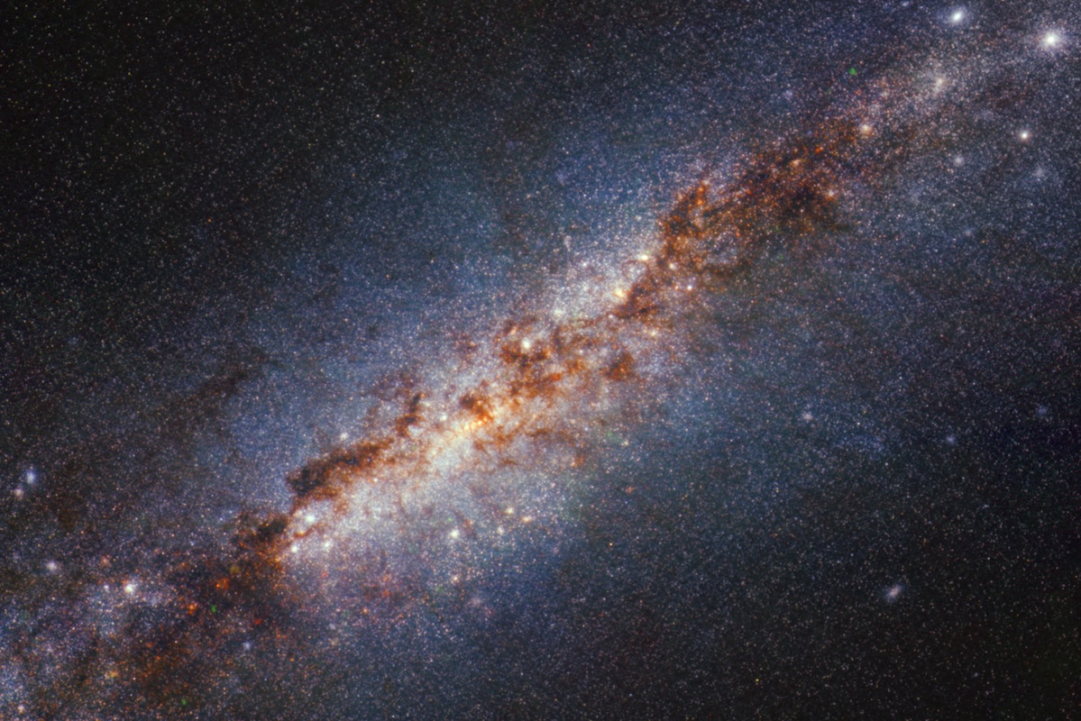 A galaxy with a ban of stars, bright spots and cosmic clouds appear from the blackness of space.