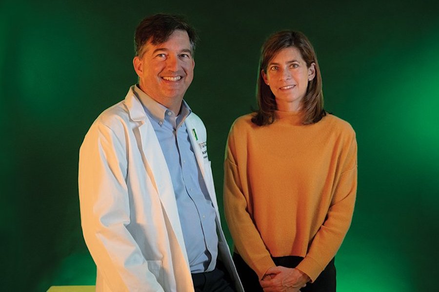 A medical doctor and a scientist stand together against a backdrop
