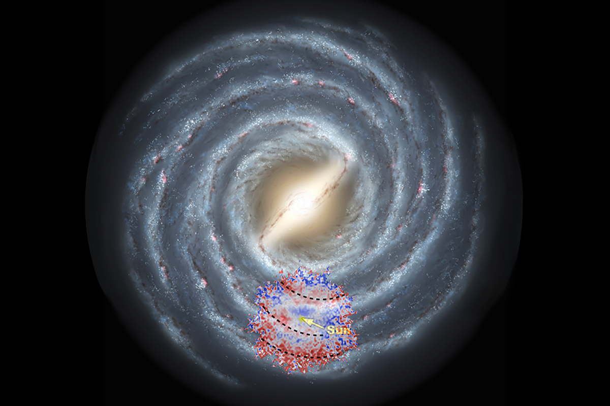 A spiral galaxy floats in the black background of space with red and blue dots sprinkled over one section