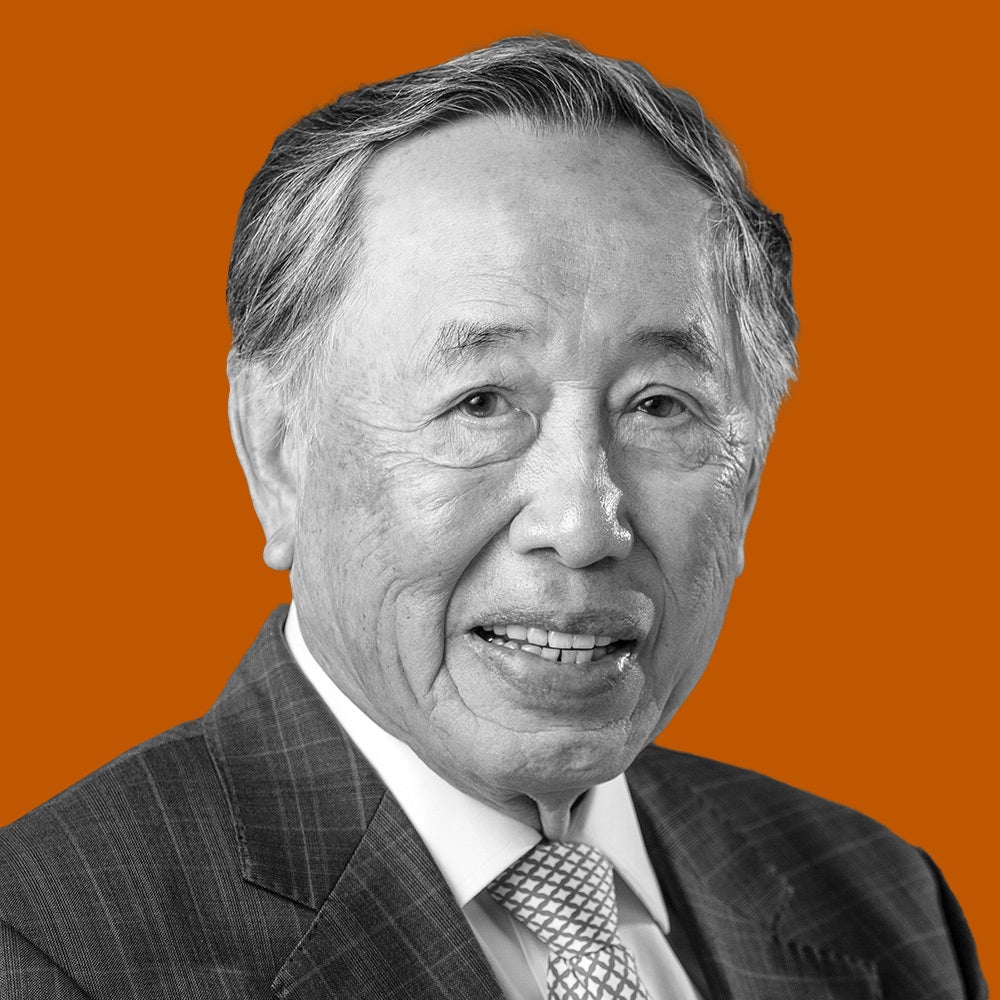 An older gentleman in a suit smiles for the camera.